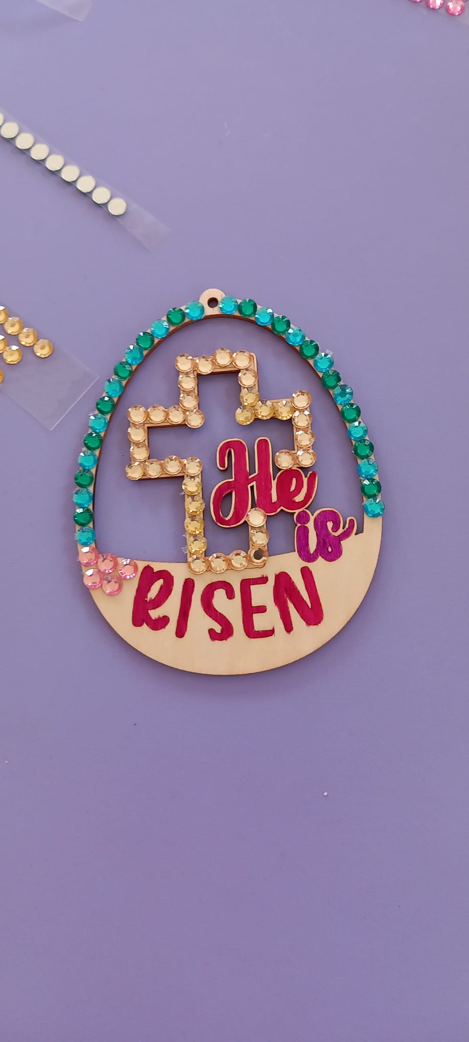 Handcrafted egg decoration with the words "He is Risen" and a cross inside.
